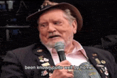 a man with a beard is talking into a microphone with the words been known quite well by home below him