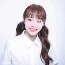 the girl is wearing a white shirt and ponytail and smiling for the camera .