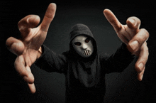 a man wearing a white mask and a black hoodie reaches out his arms