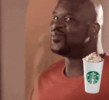 a man in a red shirt is next to a starbucks cup with whipped cream on it