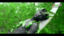 a man is laying on a tree branch with leaves around his neck and a bmg officer logo in the background