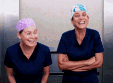 two nurses wearing scrubs and hats are laughing together