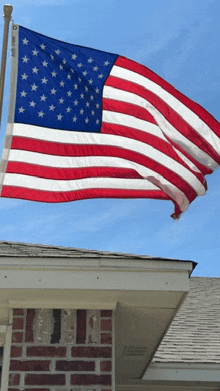 a large american flag is flying over a brick house