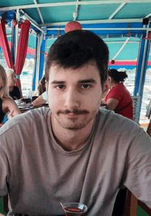 a man with a mustache is sitting at a table with a bowl of food in front of him