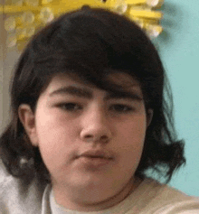 a close up of a young boy 's face with long hair making a funny face .