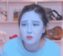 a woman with blue paint on her face looks sad .