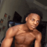 a shirtless young man is sitting in a chair in a living room .