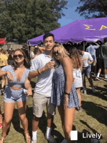 a group of people are posing for a picture in front of a purple tent with the letter z on it