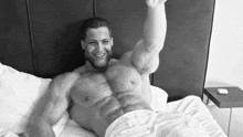 a shirtless man is laying on a bed with his arm up in the air .