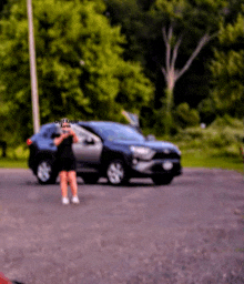 a blurry photo of a woman standing in front of a car with the name karen on the bottom right