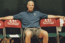 a man sits in a row of chairs that say aau nationals on them