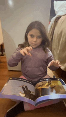 a young girl is reading a book about birds