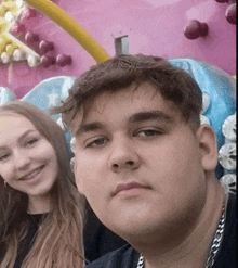 a man and a woman are posing for a picture in front of a carnival ride .