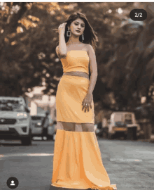 a woman in a yellow dress is standing in front of a white car