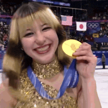 a woman in a gold dress is holding a gold medal and smiling
