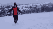 a woman in a red jacket and black pants is running through the snow