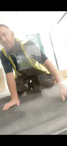 a man in a safety vest is kneeling on a counter