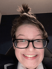 a young man wearing glasses and a ponytail makes a funny face