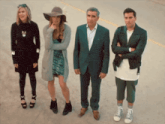 a man in a suit and a woman in a hat stand next to each other