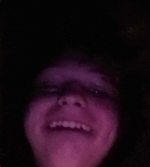 a close up of a person 's face with a purple light behind it .