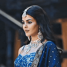 a woman wearing a blue top and silver jewelry is looking down