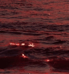 a close up of a body of water with red waves and a red sky in the background .