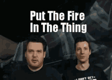 a couple of men standing next to each other with the words `` put the fire in the thing '' .