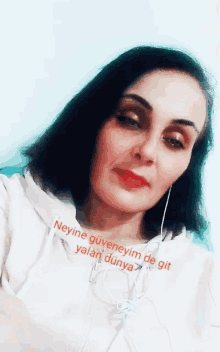 a woman is wearing headphones and a white hoodie with the words neyine güveneyim de git yalan dünya on it