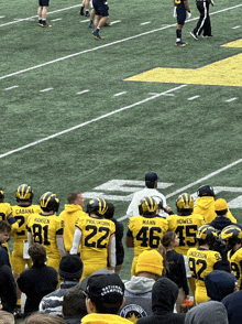 a group of football players wearing yellow uniforms with the number 22 on the back stand on a field