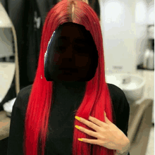 a woman with long red hair and yellow nails is standing in a room .