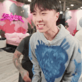 a young man wearing a hoodie with a blue heart on it smiles