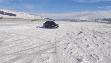 a car is driving on a snowy road with mountains in the back