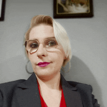 a woman wearing glasses and a red lipstick looks at the camera