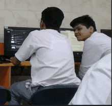 two boys are sitting in front of a computer monitor