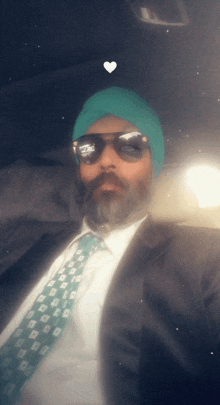 a man wearing a green turban and sunglasses looks at the camera