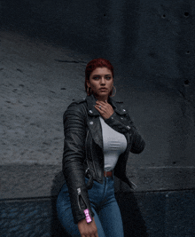 a woman with red hair wearing a leather jacket and jeans