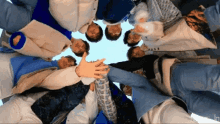 a group of people standing in a circle with their hands on each other