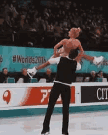 a man is carrying a woman on his shoulders while she is skating on ice .