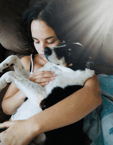 a woman laying on a couch holding a dog