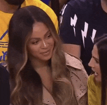 a woman is sitting in a crowd of people watching a basketball game .