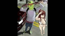 a man in a shrek mask and a woman in a bikini are standing next to each other on a street .