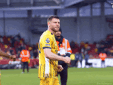 a soccer player wearing a yellow jersey that says premier league