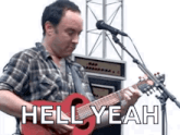 a man is playing a red guitar in front of a microphone and says `` hell yeah '' .