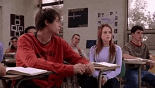 a boy and a girl are sitting at desks in a classroom .