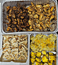 several trays of food including corn on the cob