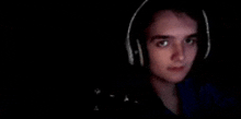 a young man wearing headphones is looking at the camera in the dark .