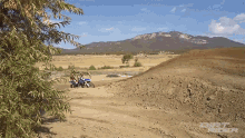 a person riding a dirt bike on a dirt road with mountains in the background and the word dirt on the bottom