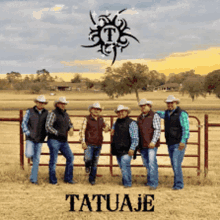 a group of men in cowboy hats are standing in front of a fence with the word tatuaje on it