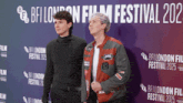 two people standing in front of a sign that says bfi london film festival 202