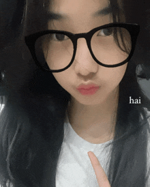 a girl wearing glasses and a white shirt has the word hai on her face